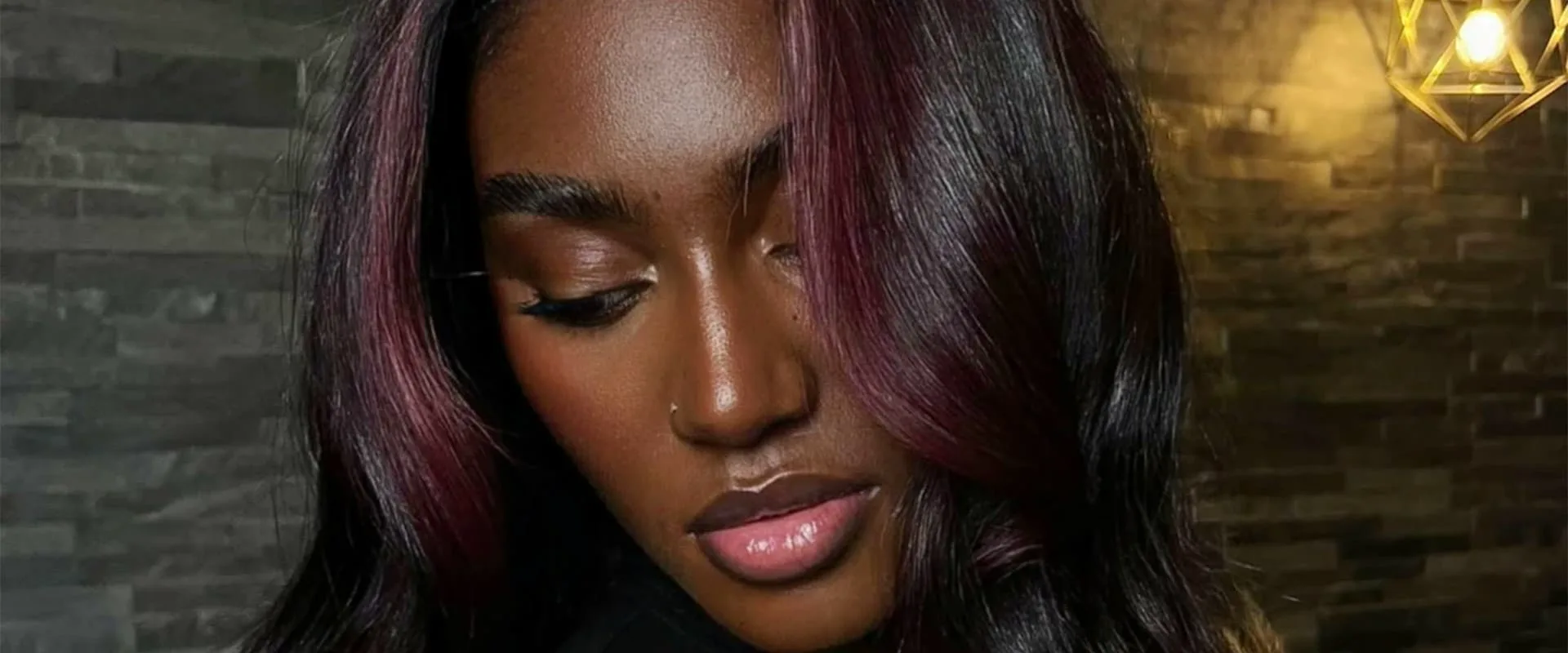 Balayage aux reflets prune sur cheveux texturés, réalisé au salon