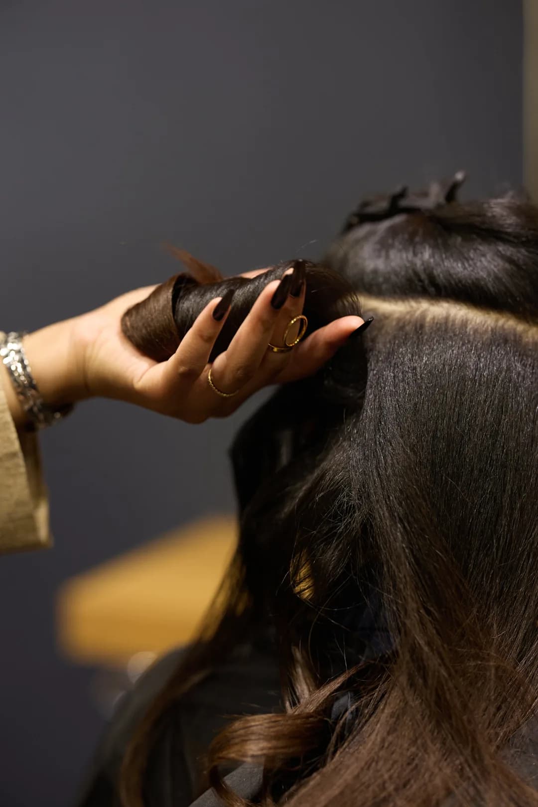 Geste de finition : mèche lisse et brillante enroulée à la main après un lissage
